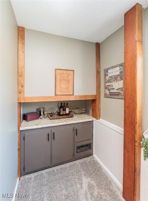 bar featuring a dry bar, light colored carpet, and a wainscoted wall