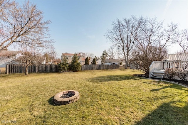 view of yard featuring a wooden deck, a fire pit, and fence