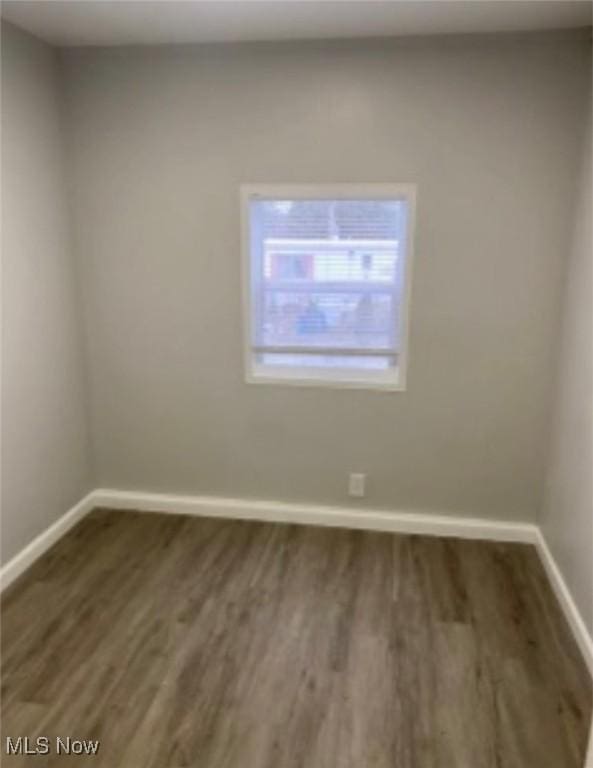 spare room featuring dark wood-style floors and baseboards