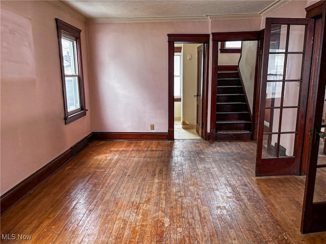 spare room featuring crown molding, baseboards, stairs, hardwood / wood-style flooring, and a textured ceiling