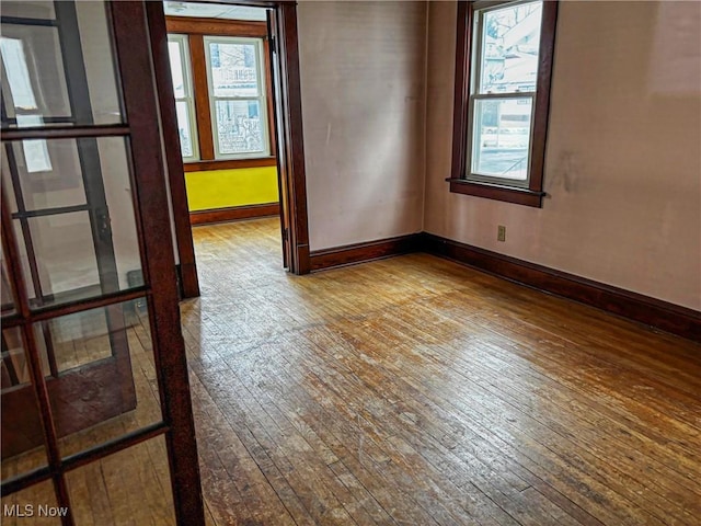 spare room featuring baseboards and hardwood / wood-style flooring