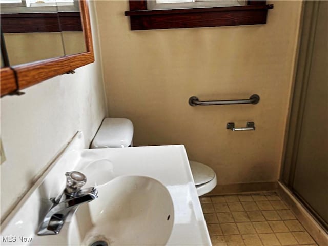 bathroom featuring a sink, baseboards, toilet, and tile patterned flooring