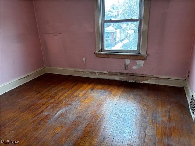 spare room with baseboards and wood-type flooring