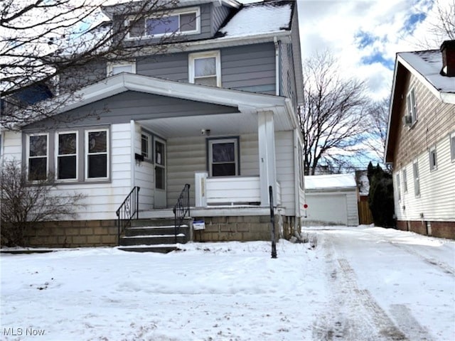 traditional style home with a porch, an outbuilding, and a detached garage