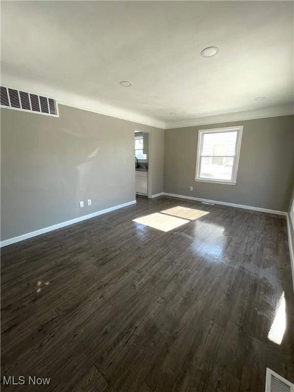 unfurnished room with dark wood finished floors, baseboards, and visible vents