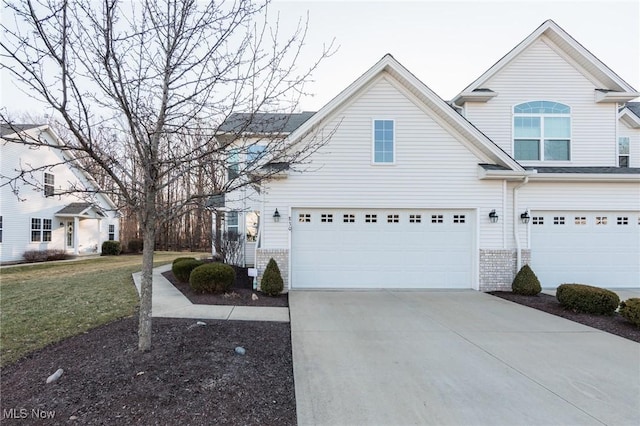 traditional-style home with a garage, a front yard, brick siding, and driveway