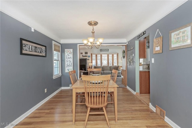 dining room with visible vents, baseboards, a notable chandelier, and light wood finished floors