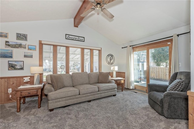 living room with a wainscoted wall, carpet floors, a ceiling fan, and vaulted ceiling with beams