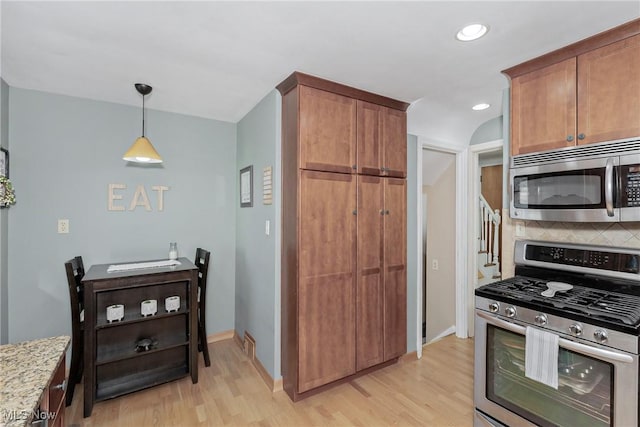 kitchen featuring decorative backsplash, light wood-style flooring, light stone counters, and stainless steel appliances