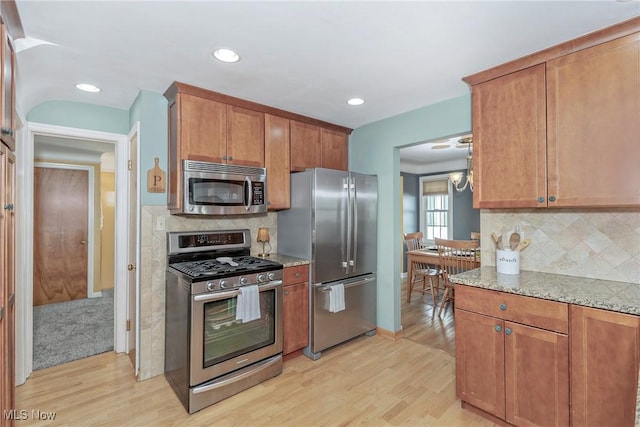 kitchen featuring appliances with stainless steel finishes, light wood-type flooring, and light stone countertops