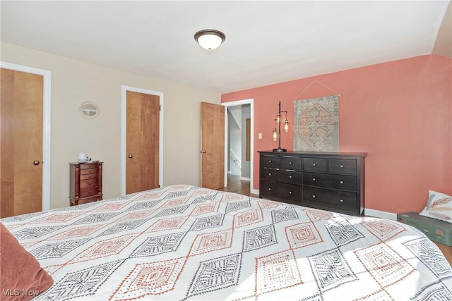 bedroom featuring lofted ceiling and baseboards