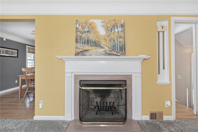 details with visible vents, baseboards, wood finished floors, and a fireplace