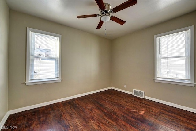 spare room with visible vents, baseboards, and dark wood finished floors