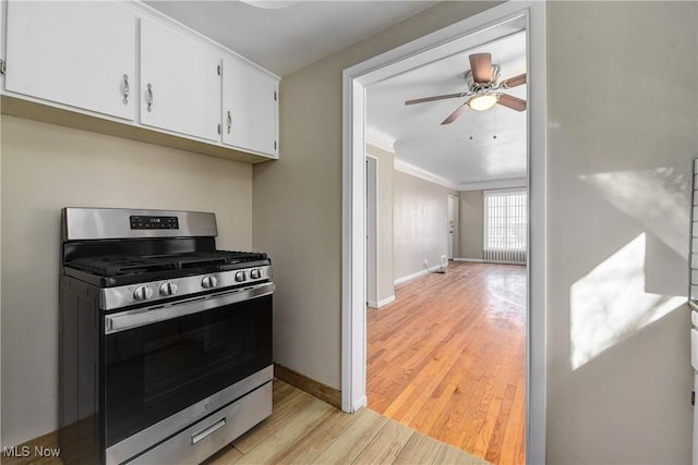 kitchen with a ceiling fan, baseboards, white cabinets, light wood-style floors, and stainless steel gas range oven