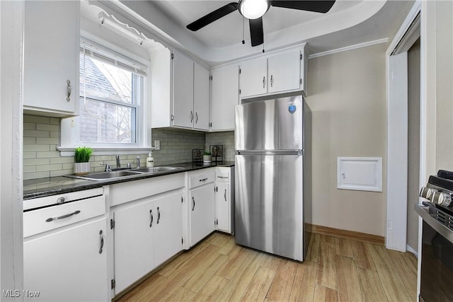 kitchen with dark countertops, a sink, freestanding refrigerator, and range