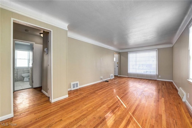 unfurnished room featuring light wood finished floors, visible vents, and crown molding