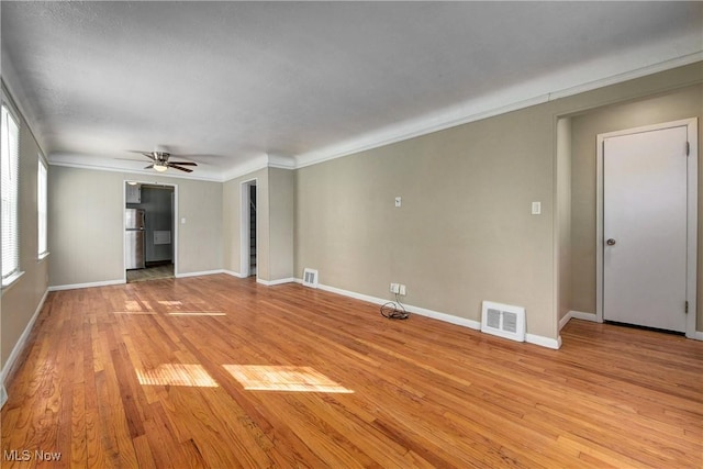 empty room with light wood-type flooring, visible vents, ornamental molding, and ceiling fan