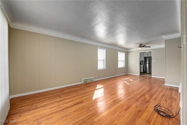 unfurnished living room featuring visible vents, baseboards, ceiling fan, ornamental molding, and light wood-style flooring