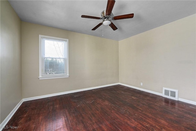 spare room featuring visible vents, baseboards, dark wood-type flooring, and ceiling fan