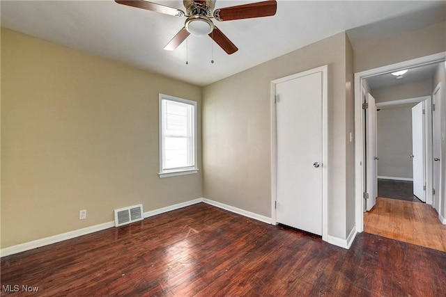 unfurnished bedroom with hardwood / wood-style floors, baseboards, visible vents, and a ceiling fan