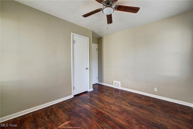 spare room featuring visible vents, baseboards, dark wood-type flooring, and a ceiling fan