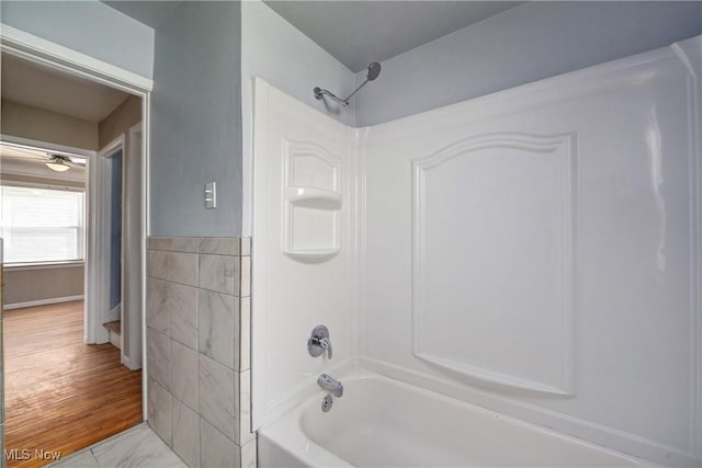 bathroom featuring marble finish floor, tile walls, and shower / bathtub combination