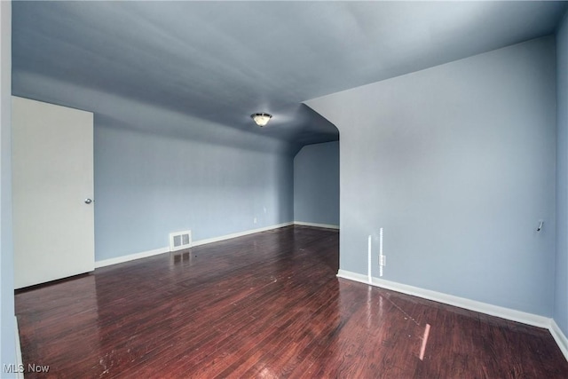 spare room with visible vents, lofted ceiling, baseboards, and wood finished floors