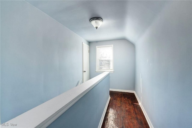 corridor with dark wood-type flooring, an upstairs landing, baseboards, and lofted ceiling