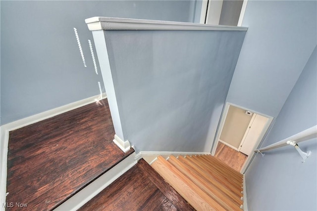 staircase featuring wood finished floors and baseboards