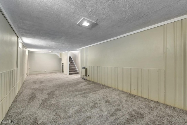 finished basement featuring stairway, radiator, carpet flooring, and a textured ceiling