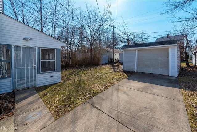 view of yard featuring a detached garage, an outbuilding, and concrete driveway