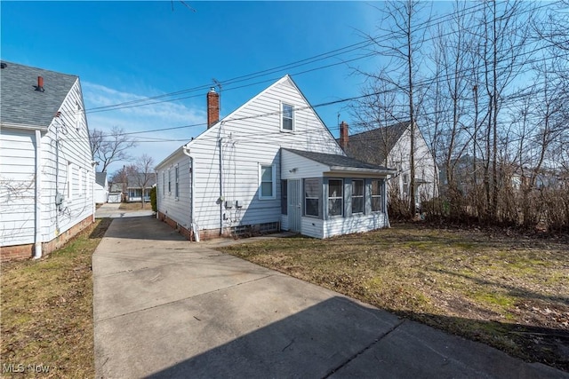 view of side of home with a chimney and a sunroom