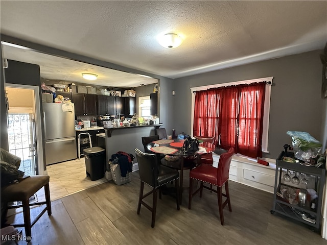 dining space featuring a textured ceiling, a healthy amount of sunlight, and wood finished floors