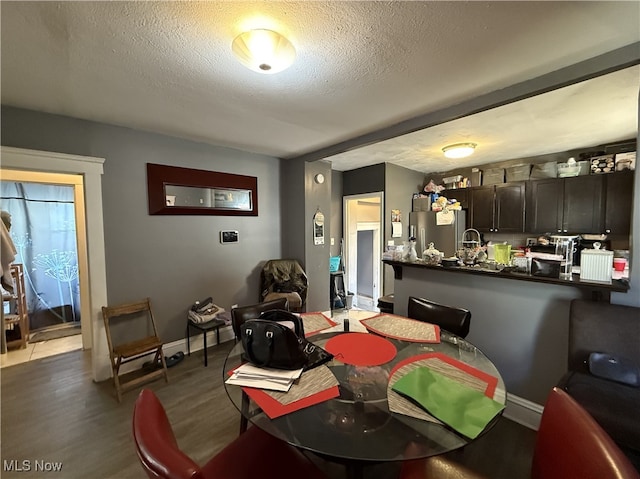 dining space with a textured ceiling, baseboards, and wood finished floors