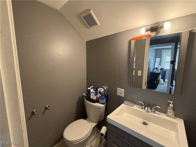 bathroom with vanity, lofted ceiling, toilet, and visible vents