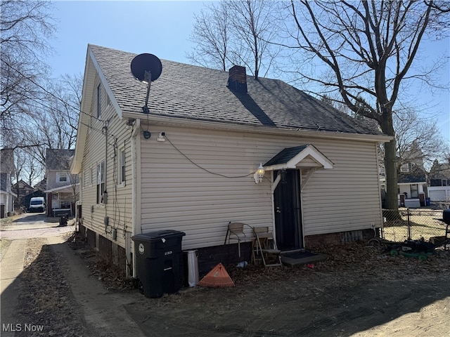 back of property featuring fence, a chimney, and a shingled roof