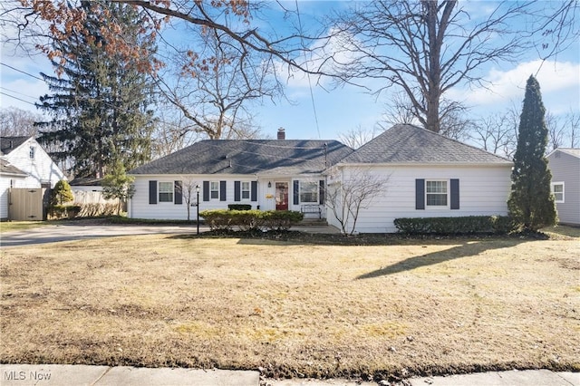 ranch-style home featuring a chimney, a front yard, and fence