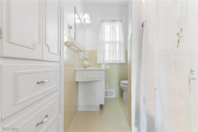 full bathroom with visible vents, a sink, tile patterned floors, toilet, and tile walls