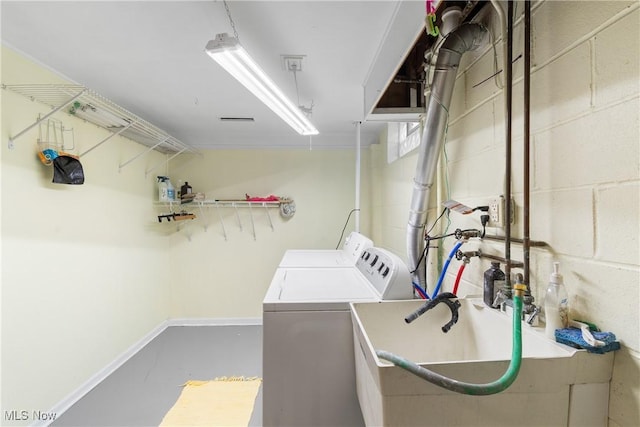 laundry area featuring a sink, concrete block wall, and washer and clothes dryer