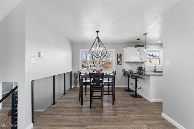 dining room with a chandelier, baseboards, and dark wood finished floors