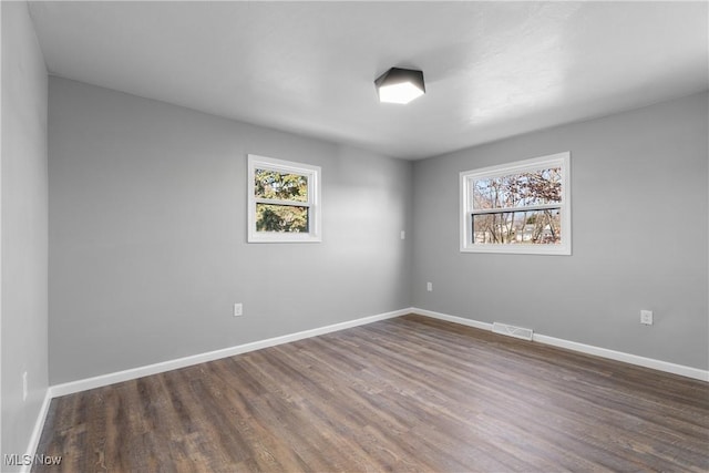 unfurnished room featuring wood finished floors, baseboards, and visible vents