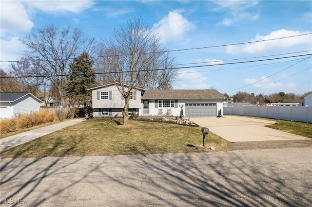 split level home featuring a garage, driveway, a front yard, and fence