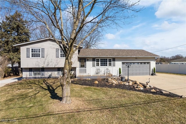 tri-level home featuring fence, a front yard, covered porch, driveway, and an attached garage