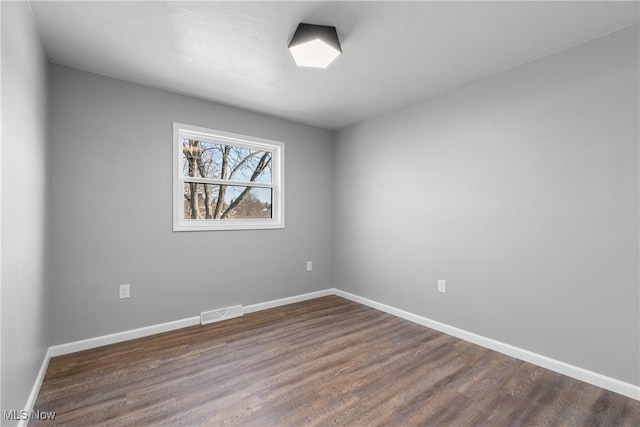 unfurnished room featuring visible vents, baseboards, and dark wood-type flooring