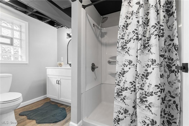 bathroom with vanity, wood finished floors, baseboards, a shower stall, and toilet