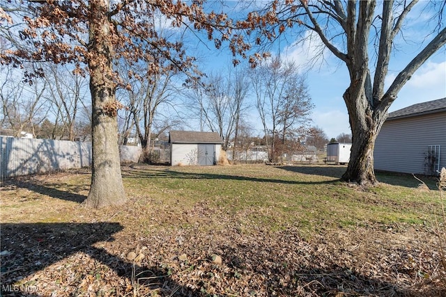 view of yard featuring an outbuilding, fence, and a shed