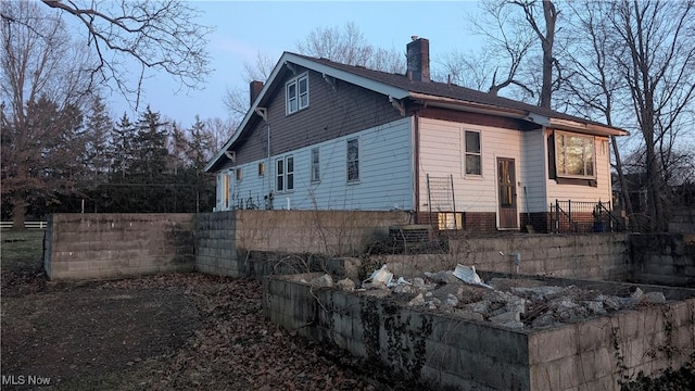 view of side of property featuring a chimney and fence