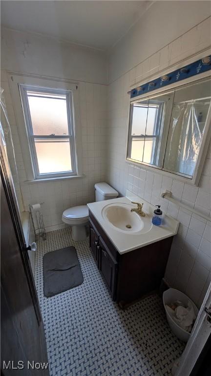 bathroom featuring vanity, tile walls, toilet, and tile patterned flooring