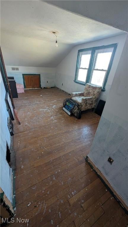 additional living space featuring visible vents, lofted ceiling, and hardwood / wood-style floors