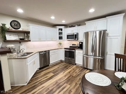 kitchen with white cabinetry, open shelves, appliances with stainless steel finishes, and a sink